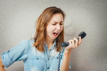 woman talking on the phone, angry shouts into the phone. isolated on gray background