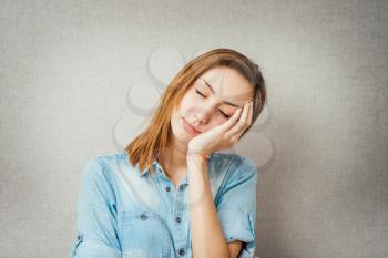 young woman pretending sleep gesture with the two hands joined