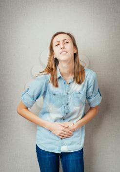 Portrait of a beautiful young woman having pain in her stomach while