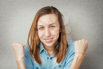 portrait of young woman gesturing victory against a grey background