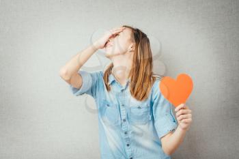 girl holding a paper heart and suffers