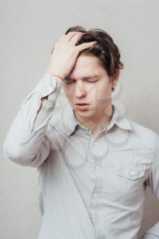 Closeup portrait of a upset young man with hand on his head