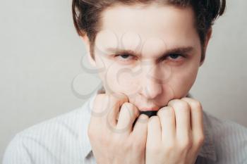 Closeup portrait of a young handsome man biting his finger nails with a craving for something or anxious. Negative human emotion facial expression feeling