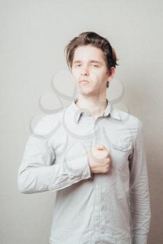 Young handsome man is swearing allegiance with his hand, fist on chest. Closeup portrait arrogant, self important, stuck up, napoleon complex, short man syndrome guy Emotion facial expression feeling