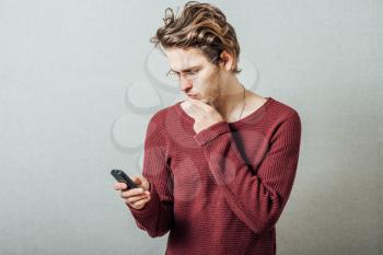 A man reading bad news on the phone. On a gray background.