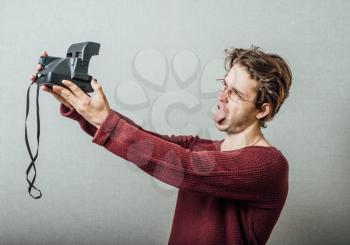 Cheerful selfie. Cheerful young man  making photo of himself while standing against grey background