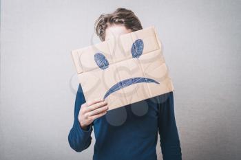 Young man with a cardboard on his head with sad face