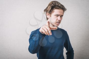 Man shows a finger forward. On a gray background.