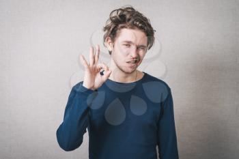 A man shows gesture okay. Gray background.
