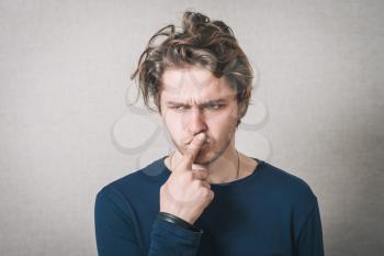 Man thinks finger to his mouth. Gray background