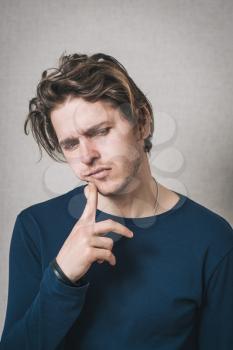 Man thinks finger to his mouth. Gray background