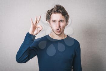 A man shows gesture okay. Gray background