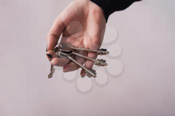 Woman hand holding keys. Gray background
