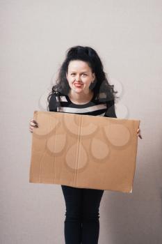 A woman holds a blank kraft paperboard. Gray background