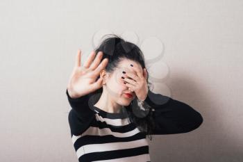 Woman showing a stop hand and closes her eyes. Gray background.
