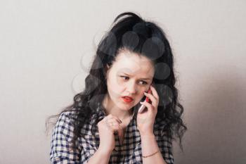 Woman talking on a cell phone, bad news surprised. Gray background
