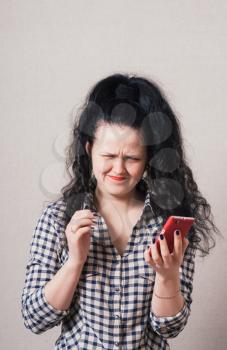 Woman reading sad message on the phone. On a gray background.