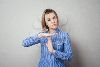 Serious girl gestures timeout, isolated on grey