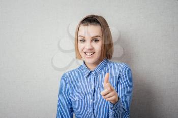 Portrait of beautiful teenager girl pointing with index finger and laughing at the camera