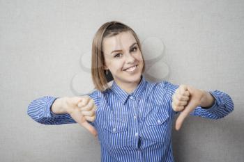 Happy smiling young woman showing thumbs down gesture
