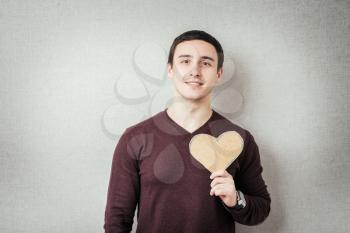 A young man holding a red heart in his hands