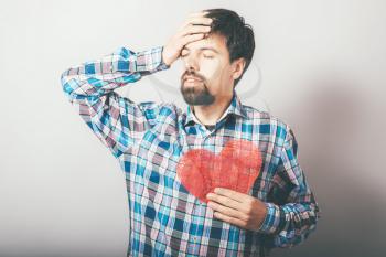 a man frustrated and holding a heart
