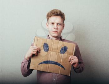 man, holding a picture of a sad smiley
