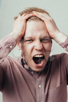 man holding his head and screaming