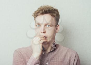 portrait of thinking man with fingers in mouth, biting fingernail. Negative emotion, facial expression