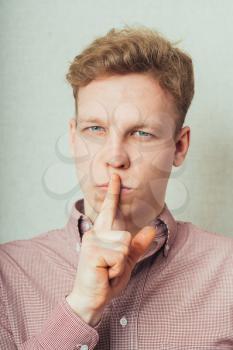 man put his index finger to his lips, indicating quiet