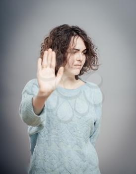 Serious young woman showing stop gesture, isolated 