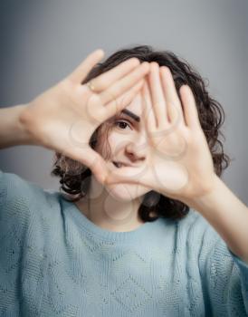 Looking of happy woman through frame of fingers