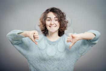 Closeup portrait  mad young woman, showing loser sign,  giving thumbs down isolated.  emotion, facial expression, signs, symbols, feeling
