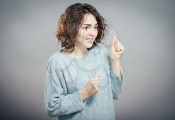 Closeup portrait, young, curly, brown hair woman, gesture with hand fists, isolated grey wall background. Positive human emotion facial expression feelings, attitude, symbol.