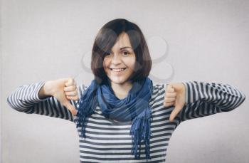 Happy smiling young woman showing thumbs down gesture