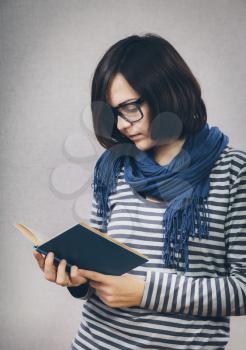 Portrait of young woman wearing glasses, reading book