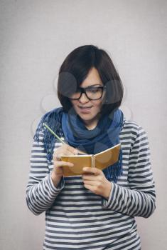 young woman in glasses writes something in a notebook