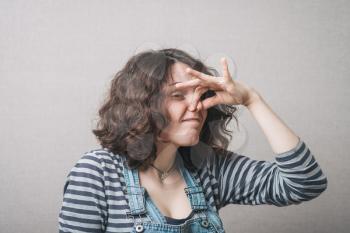 The woman closed her nose from the stench, bad smell. Gray background