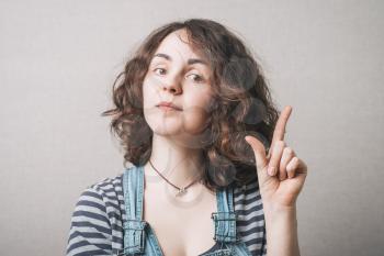 Woman shows up the index finger idea. Gray background