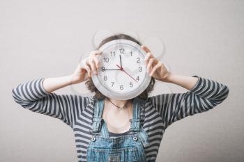 Woman holding a clock instead of a head. Gray background