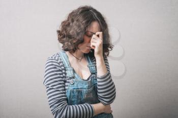 Woman sad, saddened, bowed her head. Gray background