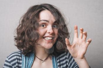 Woman playfully scared hand grimace. Gray background