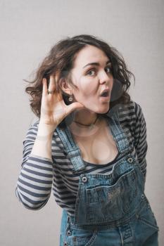 Woman with hand near ear can not hear. On a gray background.