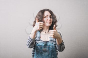 Woman showing two thumbs up. On a gray background.