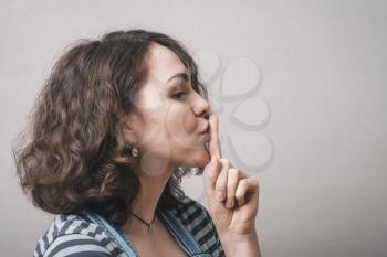 Beautiful woman with secret  finger over lips. 