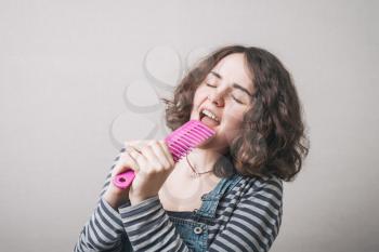 girl  sings, using a hairbrush for hair instead of a microphone