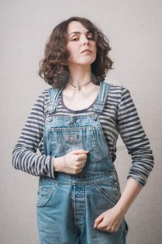 a woman walks, dressed in overalls