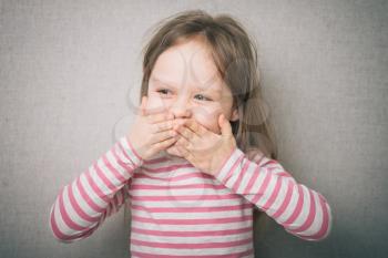 surprised little girl covered his mouth with his hands