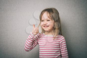 Beautiful little girl inshows finger as sign that everything is fine