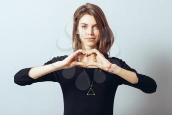 Happy smiling beautiful young woman showing heart symbol gesture, isolated